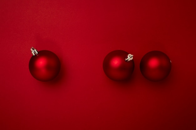 복사 공간이 있는 빨간색 배경에 빨간 크리스마스 공 장식. 새 해 인사말 카드입니다. 미니멀한 스타일
