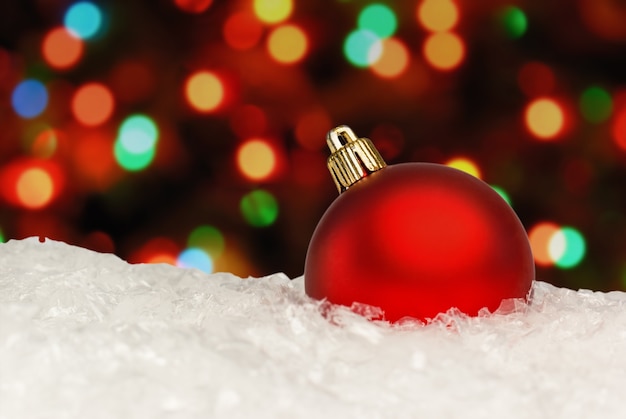 夜のぼやけたクリスマスライトの焦点がぼけた背景に赤いクリスマスボール