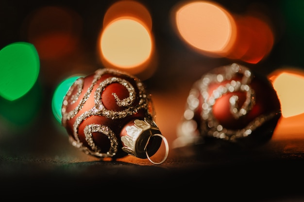 Red christmas balls on dark garland illuminated background. 