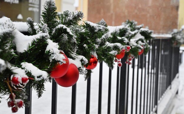 Фото Красные рождественские шары, висящие на еловых ветвях, покрытых снегом, новогоднее дерево с магическими украшениями