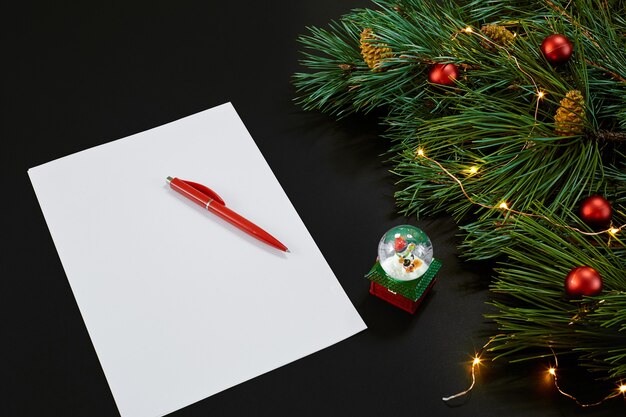 Photo red christmas balls and notebook lying near green spruce branch on black background top view space f...