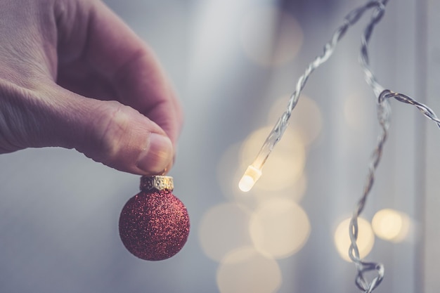 手で保持している外の光沢のある背景に装飾が施された赤いクリスマス ボール