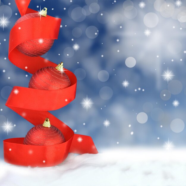 Red Christmas balls with ribbon on snowy background