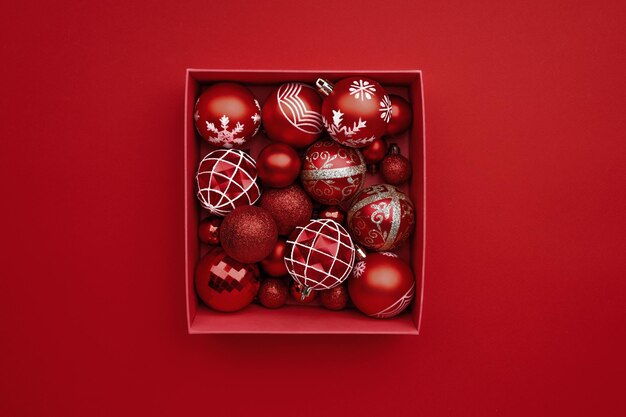 Red christmas baubles decoration in the box on red background with copy space