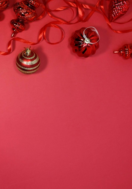 Red Christmas baubles decoration on red background with copy space. New Year greeting card. Minimal style. Flat lay.