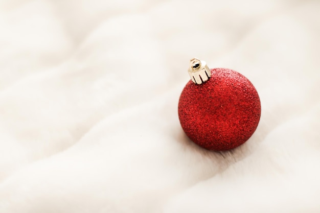 白いふわふわの毛皮の背景の豪華な冬の休日のデザインの背景に赤のクリスマスつまらないもの