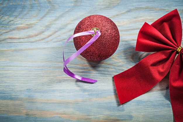 Red Christmas bow ball on wooden board holidays concept