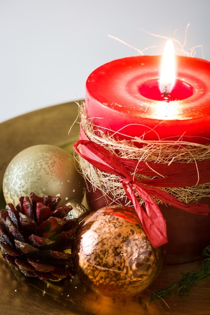 Red Christmas candle and Christmas ornaments on white