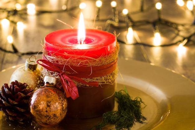 Red Christmas candle and Christmas ornaments on wood