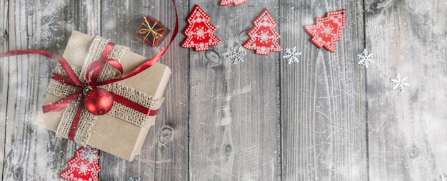 Red christmas decorations and gift box on a wooden background with snowflakes with place for text