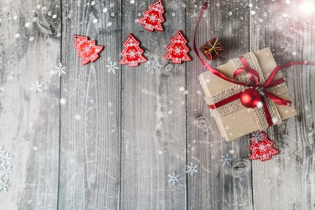 Red christmas decorations and gift box on a wooden background with snowflakes with place for text