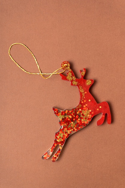 Red christmas epoxy deer on a brown background. christmas decorations on the tree. vertical photography