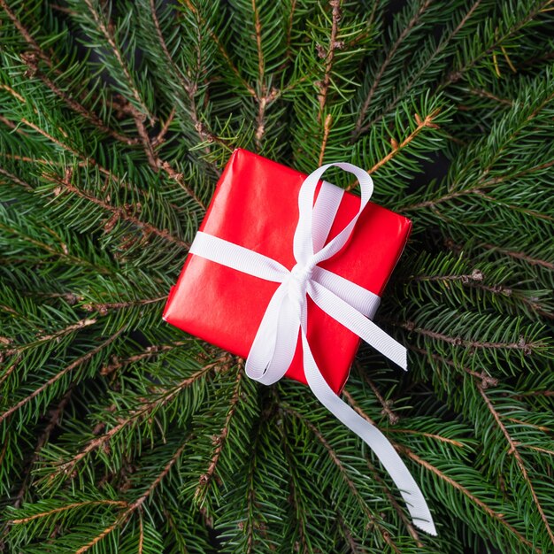 モミの木の背景、上面図に白いリボンと赤いクリスマスギフトボックス。ショッピングのコンセプト。高品質の写真