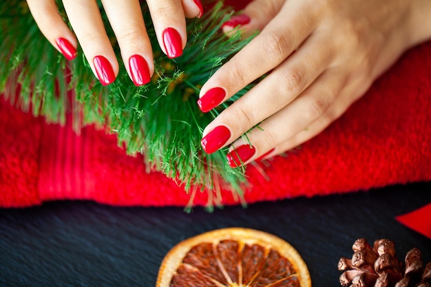 Red Christmas manicure make in beauty studio on Christmas background.