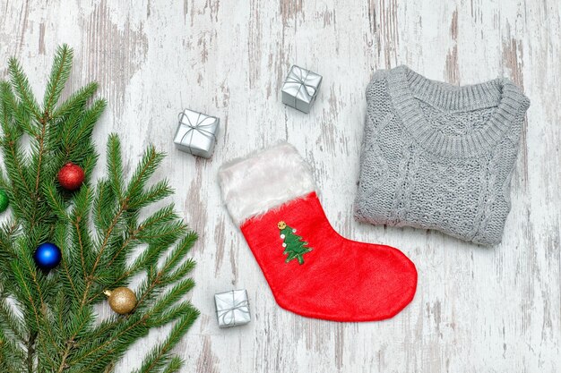 Foto calzino di natale rosso e un maglione grigio ramo di abete decorato fondo in legno concetto alla moda