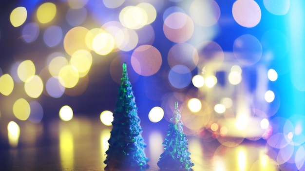 Red Christmas tree toy on a branch of a natural fir tree with lights of garlands in defocus in the background. Metal toy with slits of deer and snowflakes. Christmas, new year, copy space, bokeh.