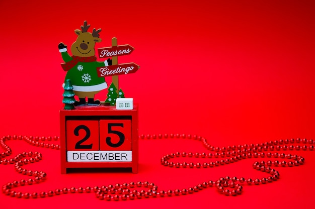 写真 赤い背景に鹿と赤いクリスマス木製カレンダー日付12月25日
