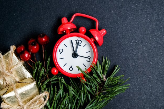 Red clock with a Christmas tree branch, hawthorn and gold gift boxes