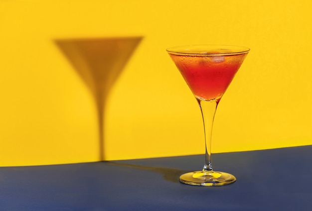 Red cocktail in a glass shaping its shadow