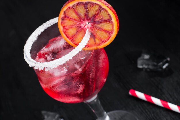 Red cocktail with ice on a black background.