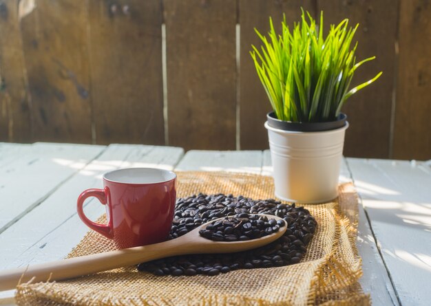 Red coffee cup and coffee beans on wooden white table