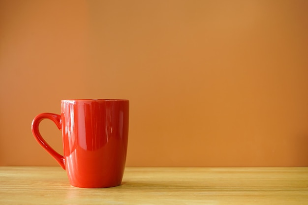 Foto tazza di caffè rossa sulla scrivania in legno con sfondo marrone