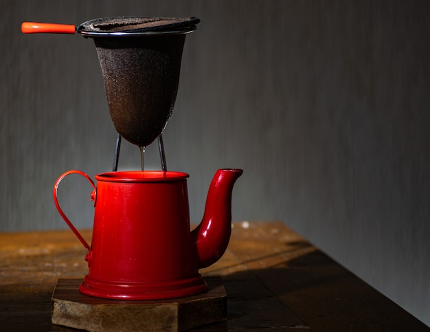 Red coffee pot and cloth strainer, with dark background