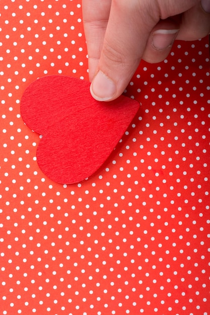 Foto oggetto a forma di cuore di colore rosso in mano su carta punteggiata