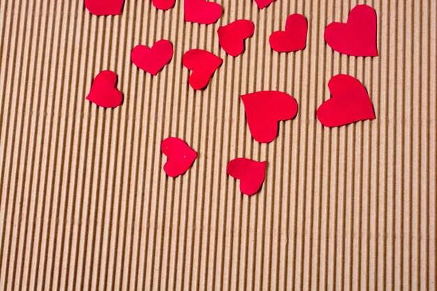 Red color paper hearts on a brown cardboard