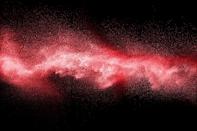 Red color powder explosion on black background.Freeze motion of red dust particles splashing.