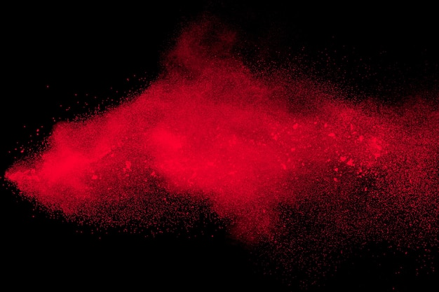 Red color powder explosion on black background.Freeze motion of red dust particles splashing.