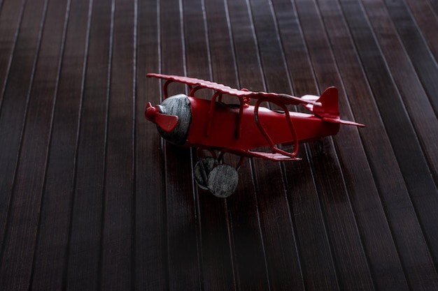 Red color toy plane is on a wooden texture