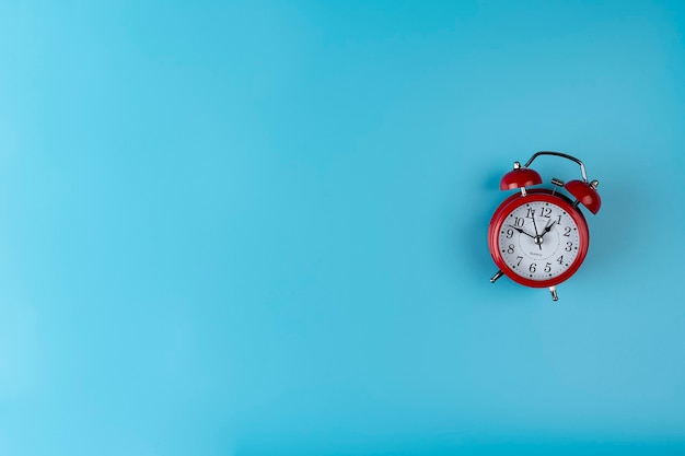 Red colored alarm clock on blue background with a copy space Concept of time image isolated clock