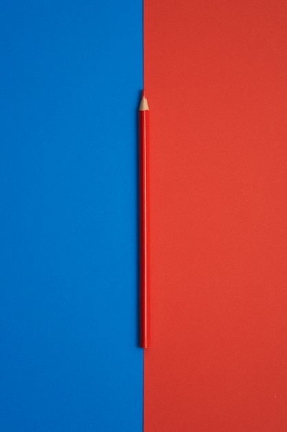 Red colored pencil isolated on blue and red table