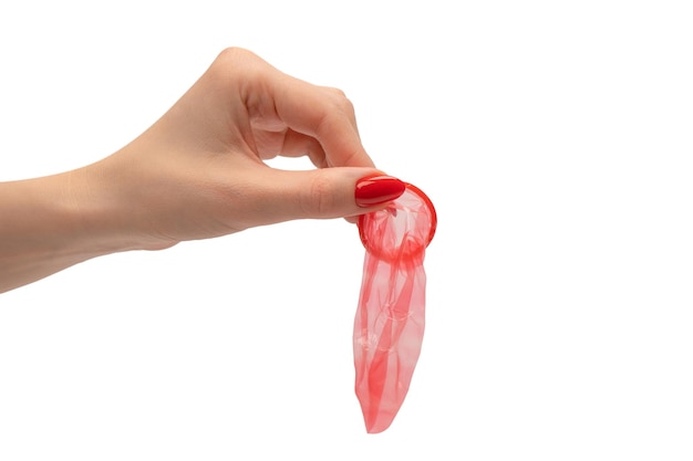 A red condom in a woman hand with red nails isolated on white background