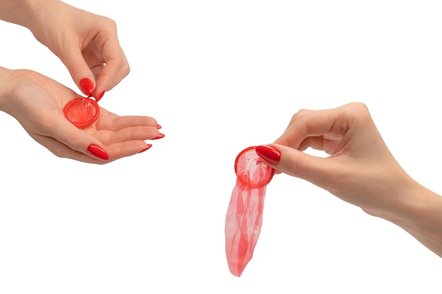 A red condom in a woman hand with red nails isolated on white background