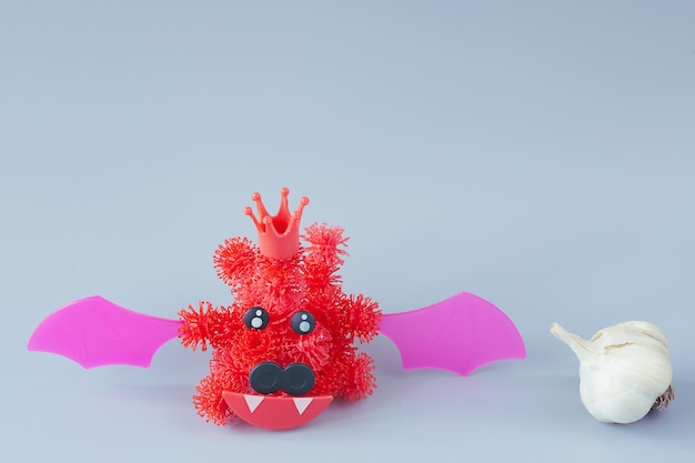 회색 배경에 벨크로가 있는 어린이 디자이너의 박쥐 형태의 빨간색 코로나바이러스. 박쥐 근처의 예배당. 야생 동물 개념 - 감염의 근원.