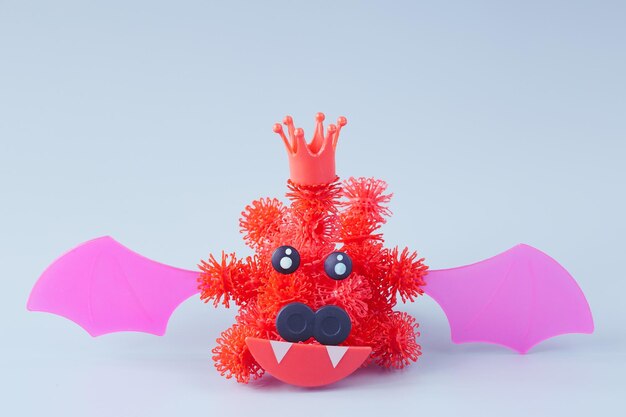 Red coronavirus in the form of a bat from a children's designer with Velcro on a gray background