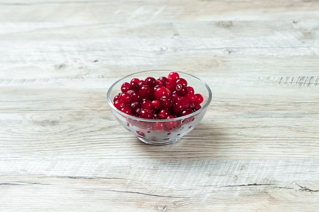 Photo red cranberries in a glass bowl on a white wooden background