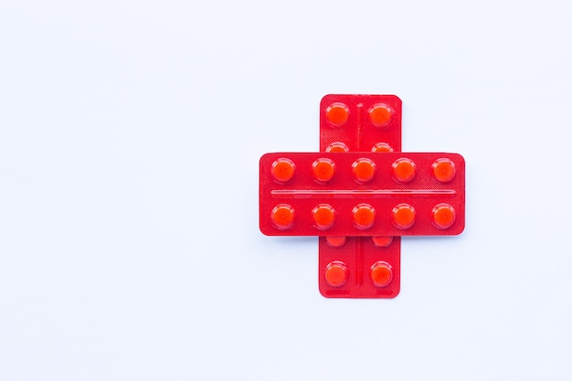Red cross made of packs with pills on a white background copy space