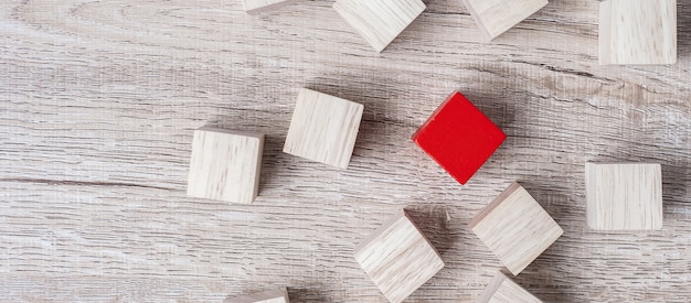 Cubo rosso diverso dalla folla di blocchi di legno.