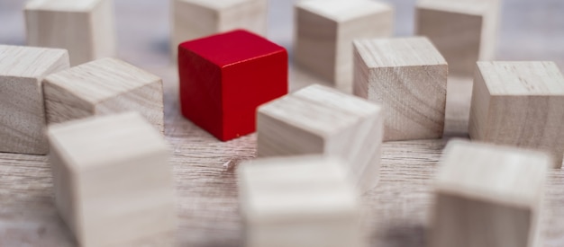 Red cube block different from crowd of wood blocks. 