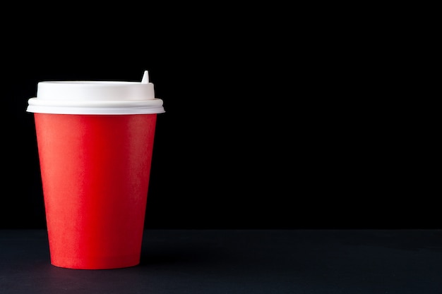 Red cup of coffee with a white cap on a black background