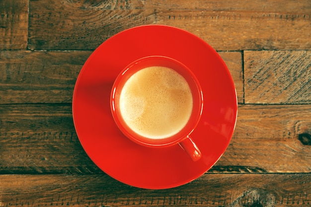 Foto tazza di caffè rossa su una tavola di legno. vista dall'alto