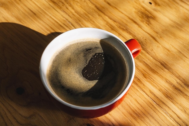 red Cup of coffee on wooden table, top view