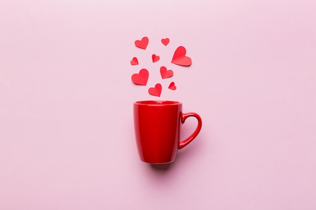 Red cup on colored background splashes of red little hearts top view with copy space