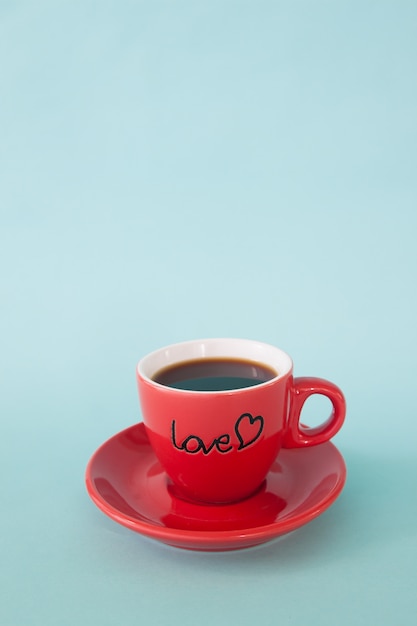 パステルカラーの背景に愛の言葉でホットコーヒーの赤いカップ