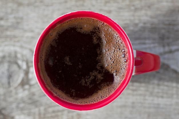 red cup of  hot coffee on the wooden table with top view