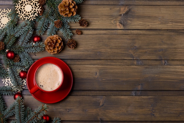 Red cup with coffee and Christmas decoration on wooden background