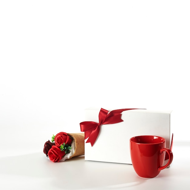 Red cup with gift box and roses on white